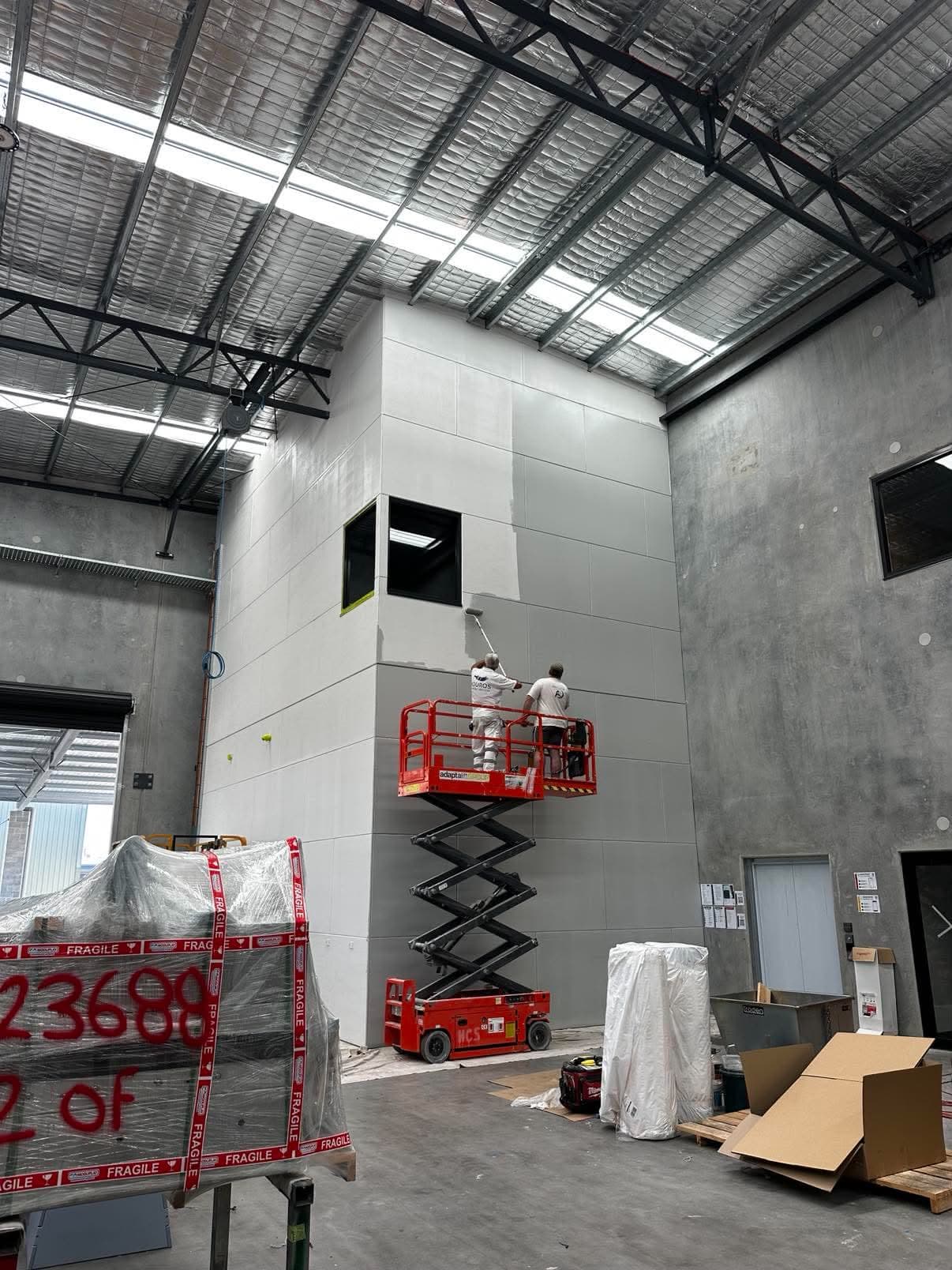 Painting a high warehouse wall from a scissor lift